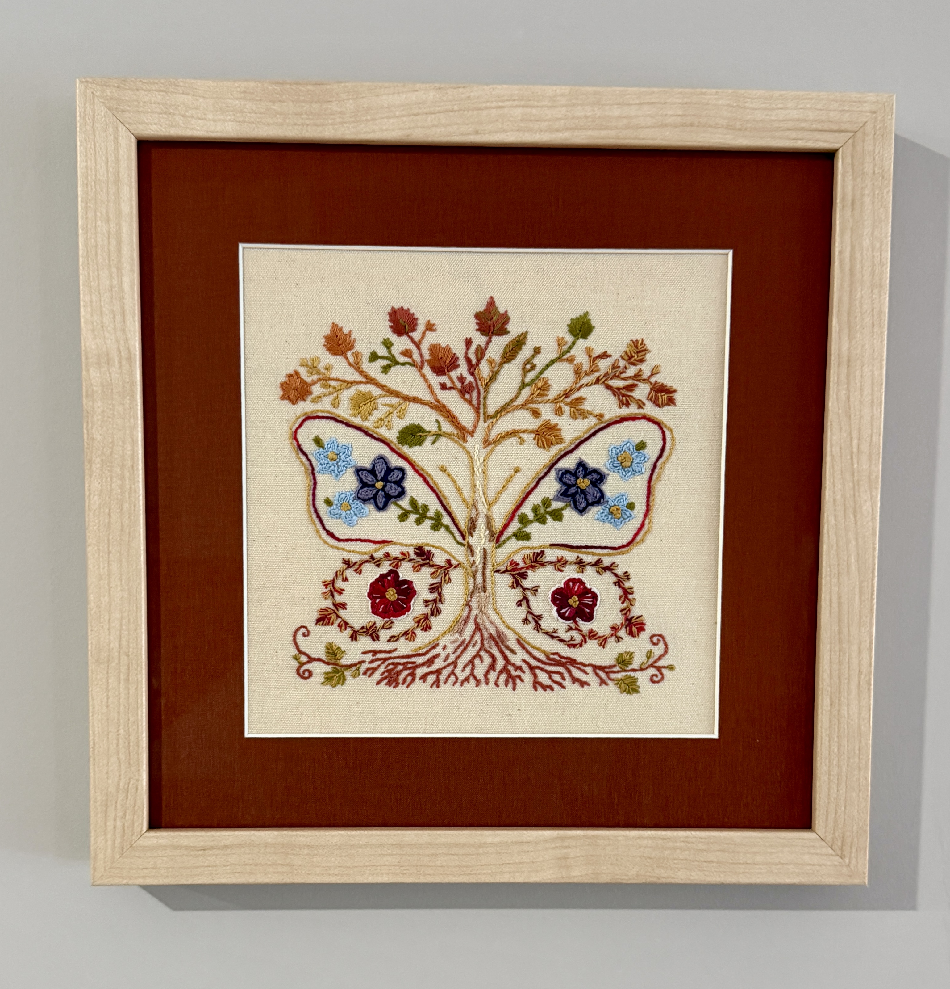 Crimson Bloom embroidered butterfly artwork in its permanent frame.